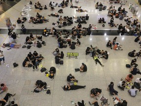Protesters sit on the floor of the arrivals hall of Hong Kong's international airport following a protest against police brutality and the controversial extradition bill on August 12, 2019.