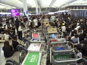 Protesters use luggage trolleys to block the walkway to the departure gates during a demonstration at the Airport in Hong Kong, Tuesday, Aug. 13.