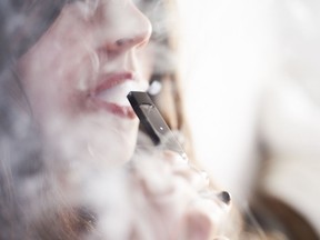 A person smokes a Juul e-cigarettein this photo illustration.