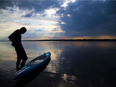 Kevin Payan heads out on the Ottawa River from Westboro beach for an evening paddle on his prone paddle board, after the rain passed on Sunday.