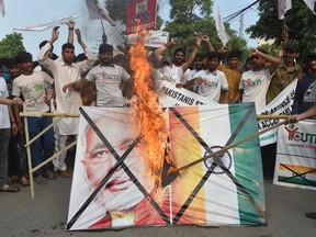 Pakistani activists of the "Youth Forum for Kashmir" group shout slogans as a a picture of Indian Prime Minister Narendra Modi and Indian flag is burned during a protest in Lahore on August 5, 2019, in reaction to the move by India to abolish Kashmir's special status.