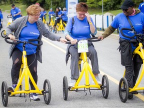 Chris Killoran breaks down with emotion as she crosses the finish line during the Ottawa Hospital Ride Sunday, flanked by volunteer Janet Mantler, left, and her close friend Fiona Amanya.