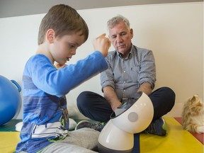 Lundy Lewis, a visiting researcher in human-AI interaction, shows James Beck, 6, an interactive robot called Jibo.