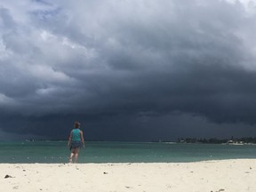 A woman walks on the beach as a storm approaches in Nassau, Bahamas, on September 12, 2019. - The National Oceanic and Atmospheric Administration (NOAA) reported a weather disturbance (95L) over the southeast and central Bahamas on September 12, 2019, which is growing better organized and is likely to form into a tropical depression or tropical storm by September 14. NOAA said the system is moving toward the northwest. If this trend continues Potential Tropical Cyclone advisories will likely be initiated later Thursday. This disturbance will bring heavy rainfall and gusty winds across portions of the Bahamas through Friday.