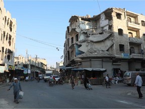 People walk near heavily damaged buildings in the rebel-held city of Idlib in northwestern Syria on Sept. 16, 2019. Hundreds of thousands have died in the regime's crackdown on its opponents.