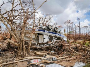 An overturned boat lies among trees in High Rock, Grand Bahama, Bahamas, on September 16, 2019. - Tropical storm Humberto gained strength on September 15 and was expected to return to hurricane force by evening, but its track now puts it far from the Bahamas and the US coast, the US National Hurricane Center said. As of midday, Humberto was 180 miles (290 kilometers) northwest of Great Abaco Island, which was devastated two weeks ago by the passage of Hurricane Dorian, and 165 miles northeast of Cape Canaveral, Florida, the NHC said in an update at 15H00 GMT.