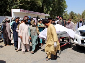 Afghan villagers carry a dead body on a stretcher outside a hospital following an airstrike in Lashkar Gah, the capital of Helmand province on September 23, 2019. - Afghanistan is investigating reports that 40 civilians, including children, were killed in an airstrike during a wedding celebration in southern Helmand province, officials said on September 23. The defence ministry said it would "share the result of the investigation" into the deaths overnight in Musa Qala district, which come less than a week after a drone killed at least nine civilians in Nangarhar province east of Kabul.