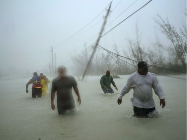 Volunteers walk under the wind and rain from Hurricane Dorian through a flooded road as they work to rescue families near the Causarina bridge in Freeport, Grand Bahama, Bahamas, Tuesday.