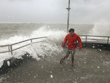 Brandon Ennis runs away from waves caused by Hurricane Dorian crashing over the jetty of the Jupiter inlet, Tuesday, in Jupiter, Fla.