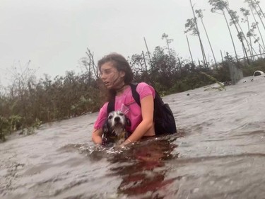 Julia Aylen wades through waist deep water carrying her pet dog as she is rescued from her flooded home during Hurricane Dorian in Freeport, Bahamas, Tuesday.