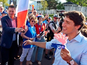 Prime Minister Justin Trudeau points to Conservative Leader Andrew Scheer while walking with the crowd during the Tintamarre in celebration of the National Acadian Day and World Acadian Congress in Dieppe, N.B., on Aug. 15, 2019.