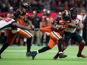 The B.C. Lions' Brandon Rutley carries the ball in front of the Ottawa Redblacks' Jeff Knox Jr., back right, as Avery Ellis, left, pulls on his jersey during a game in Vancouver on Friday, Sept. 13, 2019.