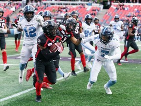 Stefan Logan #5 of the Ottawa Redblacks makes the 1st down during a runback against Robert Woodson #7 and Nelkas Kwemo #12 of the Toronto Argonauts during a CFL game in the fourth quarter held at TD Place, on September 07, 2019, in Ottawa.