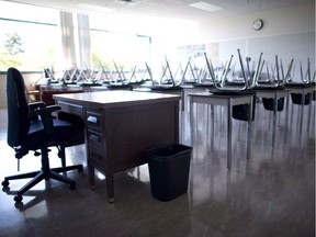 A empty teacher's desk is pictured in an empty classroom.