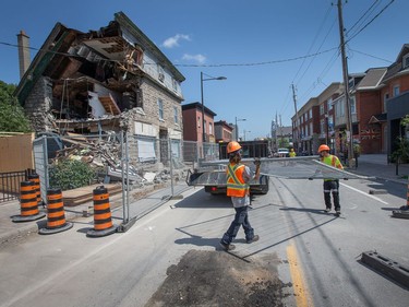 Workers have begun removing barricades, installing traffic pylons and road signage as the city prepares to open up Wellington Ave to traffic once again in front of Magee House which suffered a collapsed wall.