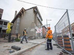 Workers remove the sidewalk barricade in front of Magee House on Wellington St. after engineers deemed the building safe following repairs to the structure of the heritage building.