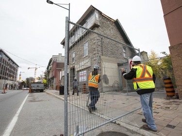 Workers remove the sidewalk barricade in front of Magee House on Wellington St. after engineers deemed the building safe following repairs to the structure of the heritage building.