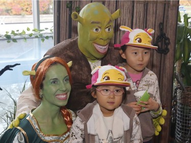 Ellie, 7, and Irene, 5, pose for a photo with Shrek and Princess Fiona at the "Trick or Treat with the Mayor" Halloween event at City Hall.