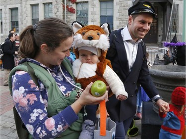 Allison Ensom, left, and Juniper, 9 months, get an apple at the "Trick or Treat with the Mayor" Halloween event at City Hall on Saturday.