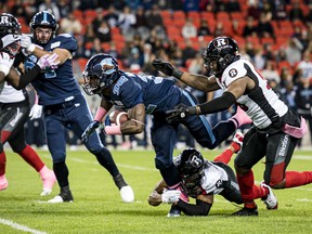 Argonauts running back James Wilder Jr. (right) is stopped by Redblacks defensive lineman Kene Onyeka and defensive back Kishawn McClain in Toronto last night.   The Canadian Press