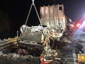 Heavy tow truck removes remains of a burned out tractor trailer on Highway 401 Thursday.