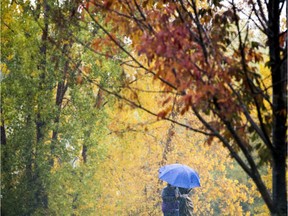 Two people snuggle together to keep dry under an umbrella.