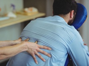 Physiotherapist giving back massage to a patient in the clinic.