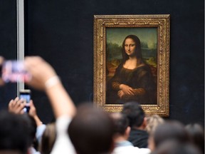 Visitors take pictures in frront of Mona Lisa after it was returned at its place at the Louvre Museum in Paris on October 7, 2019. - Leonardo da Vinci's masterpiece, the "Mona Lisa," returned to her usual spot in Paris' Louvre Museum on October 7 following a two-month renovation for the gallery housing the world's most famous painting.