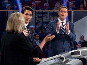 Conservative Leader Andrew Scheer, right, and Green Party Leader Elizabeth May discuss a point while Liberal Leader Justin Trudeau, centre, looks on during the federal leaders' debate in Gatineau October 7, 2019.