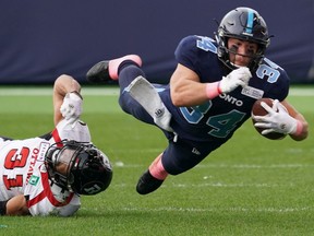 The Argos' A.J. Ouellette (34) is tackled by the Redblacks' Kevin Brown (31) during the second quarter of Saturday's game.