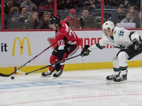 Senators defenceman Thomas Chabot skates with the puck while being pursued by Sharks winger Patrick Marleau during the first period of Sunday's game.