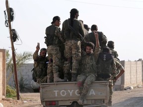 Turkey-backed Syrian rebel fighters gesture as they ride on a back of a truck in the village of Yabisa, near the Turkish-Syrian border, Syria, October 13, 2019. REUTERS/Khalil Ashawi ORG XMIT: GGG-SYR04