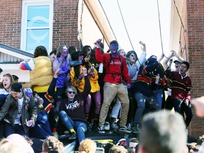Students on top of a car in a driveway on Aberdeen Street pull on wires during a massive street party. Thousands of students packed the street in Kingston's University District on Saturday, Oct. 19, 2019, during Queen's Homecoming weekend.