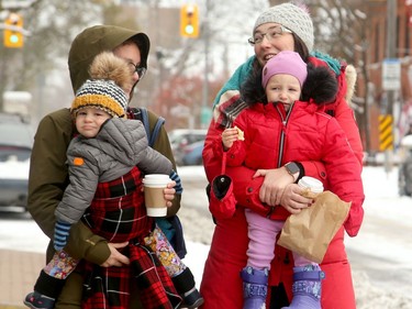 Moms Samantha Heckman (right) and Jean Sewell give their little ones (Caelan (left) and Evelyn) a boost as they made their way through the Glebe Tuesday morning following a dump of snow Monday night.