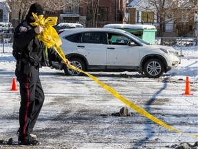 An Ottawa Police Service officer removes crime tape from a scene on Bayswater Avenue where a SUV sits with several apparent bullet holes visible on the passenger side.
