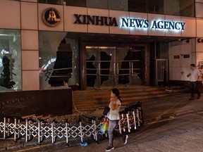 Pedestrians stands in front a vandalized entrance of Xinhua News Agency, the Chinese official news agency in Wan Chai district on Saturday in Hong Kong.