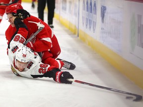 Connor Brown of the Senators reaches for the puck after getting knocked down by Dennis Cholowski of the Red Wings during the first period of Tuesday night's game in Detroit.