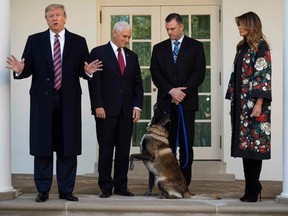 U.S. President Donald Trump (L), Vice President Mike Pence (2nd L) and First Lady Melania Trump (R) stand with Conan, the military dog that was involved in the raid on ISIL leader Abu Bakr al-Baghdadi, at the White House in Washington, D.C., on November 25, 2019.