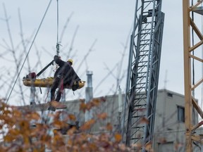A member of Ottawa Fire Services lowers a stricken crane operator to the ground on a stretcher.