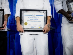 The Mission's Food Services Training Program graduates stand on stage with their graduation certificates.