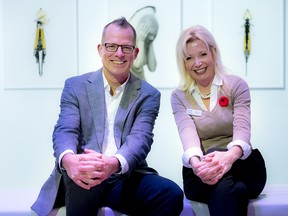 Dr. John Sinclair, a neurosurgeon with The Ottawa Hospital, and Alexandra Badzak, chief executive officer of the Ottawa Art Gallery, sitting in front of Leah Mowers’ art.