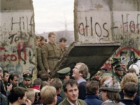 In this file photo taken on Nov. 11, 1989 West Berliners crowd in front of the Berlin Wall as they watch East German border guards demolishing a section of the wall in order to open a new crossing point between East and West near the Potsdamer Square in Berlin.