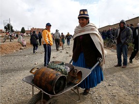 A woman carries gas canisters next to blocked petrol plant of Senkata in El Alto outskirts of La Paz, Bolivia, November 19, 2019. REUTERS/David Mercado ORG XMIT: LPZ07