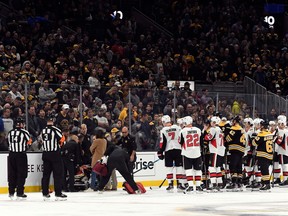 Ottawa and Boston players gather on the ice, right, as Senators winger Scott Sabourin receives attention from medical staff on the ice at TD Garden on Saturday night.