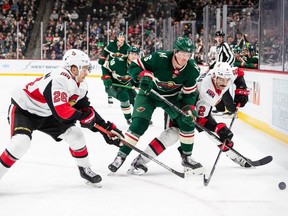 The Minnesota Wild's Ryan Donato, and Ottawa Senators defencemen Erik Brannstrom (26) and Dylan DeMelo (2) fight for the puck during the second period at the Xcel Energy Center.