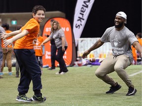 Hamilton Tiger-Cats linebacker Simoni Lawrence does a celebration dance with a student during a Jumpstart event at the RBC Convention Centre that is part of CFL Week in Winnipeg on Thurs., March 22, 2018.