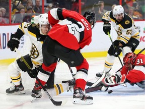 Anders Nilsson of the Ottawa Senators makes a crazy save against Danton Heinen (left) and Brad Marchand (right) of the Boston Bruins as Dylan DeMelo defends at Canadian Tire Centre on Monday.