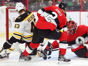 Anders Nilsson of the Ottawa Senators makes a save against Danton Heinen (left) of the Boston Bruins as Dylan DeMelo defends on Monday night.