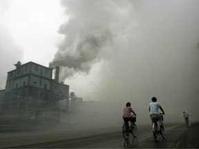 This picture taken July 18, 2006, shows cyclists passing through thick pollution from a factory in Yutian, 100km east of Beijing in China's northwest Hebei province.
