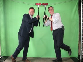 Ottawa's mayor Jim Watson (left) and Gatineau mayor Maxime Pedneaud-Jobin horse around in front of a green screen on a fake zip line at an event announcing Canada's first interprovincial zip line.